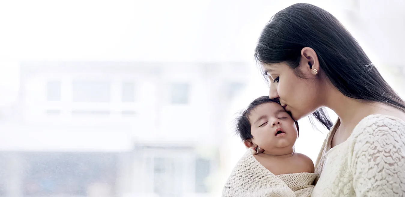 A mother kissing her newborn
